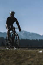 Road bike rider in spring in the Allgäu against the picturesque backdrop of the Alps, Bavaria,