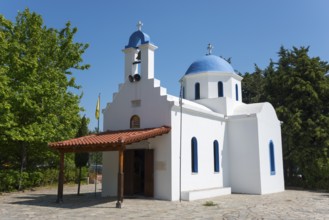 White Greek church with blue domes under a clear sky, Church of the Dormition of the Virgin Mary,