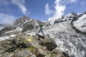 Mountaineer jumping from rock to rock, high alpine glaciated mountain landscape, La Jonction,