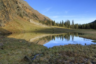 A small body of water reflects the surrounding mountains and trees, Felbertal, Mittersill,