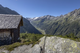 An alpine valley with mountain hut and rocky landscape under a blue sky, Hohe Tauern National Park,