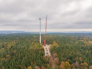 Erection of a wind turbine in a colourful autumn forest with a cloudy sky, wind farm construction