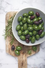 Chalkidiki olives, classic Greek green olives, in a bowl on a cutting board, top view, without