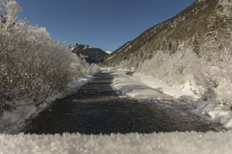 The Riss creek flowing through a snow covered landscape in the Eng valley. Sunny day with blue sky