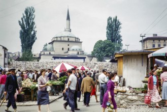 People shopping at street market with Gazi Husrev-beg mosque minaret in background, Sarajevo,