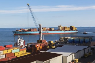 Maersk Serangoon cargo ship loaded with metal box shipping containers being guided by pilot boats