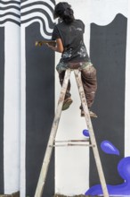 Indian artist painting a wall during the international contemporary art exhibition Kochi-Muziris