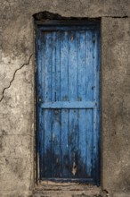 Weathered blue wooden door in an old wall with visible cracks, Canary Islands, Lanzarote, Spain,