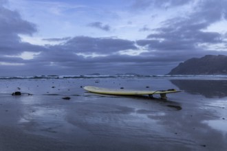 Lying surfboard on the beach with a view of the sea and an evening sky, Canary Islands, Lanzarote,