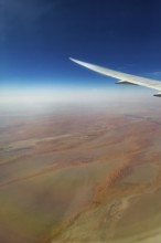 Landing approach over the desert to Abu Dhabi with the airline Etihad. View from the window of a