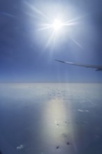 View of the Persian Gulf from the aeroplane window. Sun and clouds over the sea. Flight with the