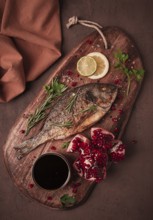 Fried dorado fish, with spices and herbs, on a wooden board, pomegranate sauce, close-up, no people