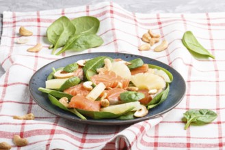 Fresh salmon with pineapple, spinach and cashew on a gray concrete background. Side view, linen