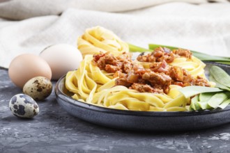 Tagliatelle bolognese pasta with minced meat on a black concrete background. side view, close up