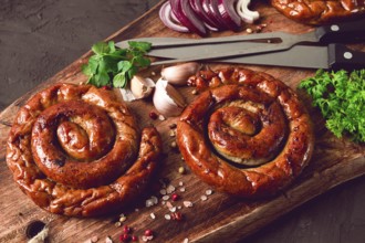 Fried spiral sausages, on a wooden board, top view, with spices, no people