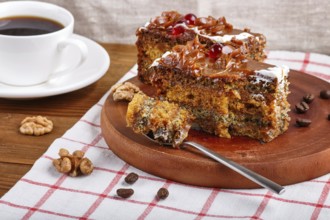 A piece of cake with caramel cream cutted with spoon on a wooden kitchen board and a cup of coffee,