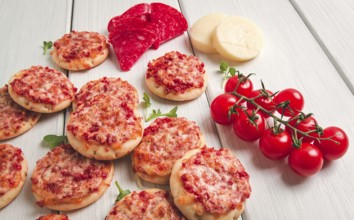 Mini pizzas, salami with mozzarella cheese, on a white table, top view, no people