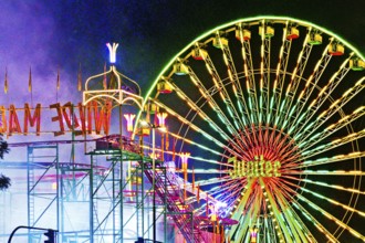 Cranger Kirmes with colourfully illuminated fairground rides and the Ferris wheel at night, Herne,