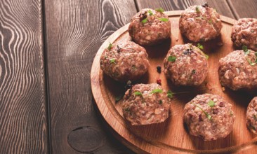 Raw meatballs, with micro greenery, on a cutting board, homemade, rustic, no people