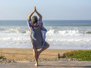 Woman performing yoga Tree pose Vrikshasanayoga, Atlantic Ocean Morocco, north Africa