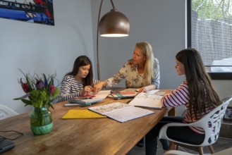 Homeschooling, during the lockdown in January 2021, mother helps her two daughters, at home,