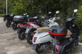 Black and white scooters including models Versilia 125 and Super B & W parked along the waterfront