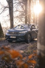 Car parked on a forest path, illuminated by low sun, Car Sharing, electric car, Volkswagen ID 5,