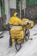 Winter weather, heavy snowfall, city centre traffic, postman with bicycle in the snow, Essen, North