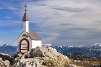 A small chapel stands on the Hochgern summit under a clear blue sky in the Chiemgau mountains in