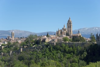 Medieval city with cathedral and historic buildings, surrounded by trees and mountains on a clear