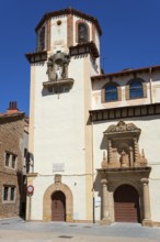 A historic building with a striking tower and elaborate decorations against a clear blue sky,