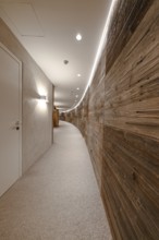 A long curved corridor with wooden panelling and modern lighting, Mayrhofen, Zillertal, Austria,