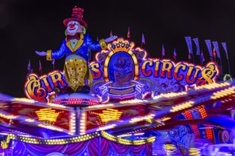 Illuminated round and elevated ride Circus Circus gondolas in motion, night shot, Oktoberfest,