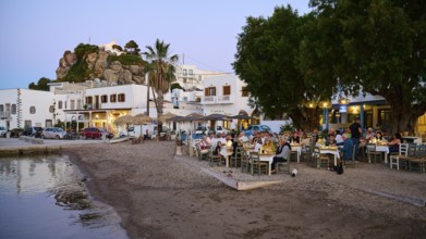 A cosy dinner on the beach, surrounded by trees and whitewashed houses, creates an atmosphere of