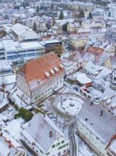 Snow-covered old town with historic buildings and red roofs, surrounded by narrow streets, police