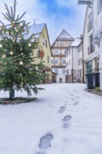 Snowy village street with footprints in the snow and half-timbered houses in the background,