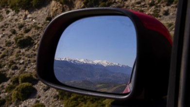 Mountain landscape in winter, reflected in the car mirror during a car journey, Lefka Ori, White