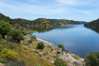 Calm river with green hills under a clear sky, peaceful landscape, confluence of the River Tiétar