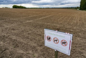 Sign on a field where crops have just been sown, with the request not to enter the field because of