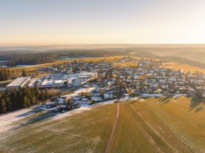 View of a snow-covered village with fields and forests, illuminated by the setting sun, Neuweiler,