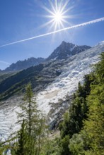 View of glacier Glacier des Bossons with sun star, behind summit of Aiguille du Midi, Chamonix,