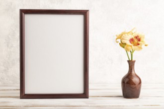 Wooden frame with orange day-lily flowers in ceramic vase on gray concrete background. side view,