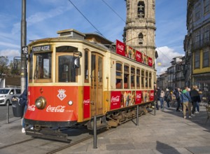 The iconic red tram number 18 pauses in front of the Clérigos Church Tower, Porto, Portugal, Europe