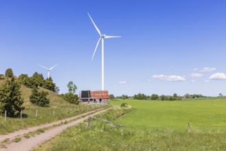 Dirt road to wind turbines in the countryside a sunny summer day with green fields