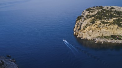 Drone shot, Small boat navigating through the clear blue water along a steep cliff, Anthony Quinn