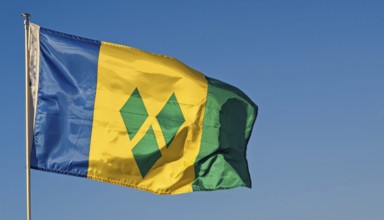 The flag of the Grenadines flutters in the wind, isolated against a blue sky