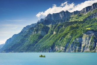 Sunny view over Lake Walen with the small chive island in the turquoise water and mountain range