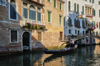 VENICE, ITALY, JULY 19, 2019: Narrow canal between colorful old houses with gondola boat with