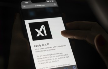 In this photo illustration, A person browses website of xAI, displayed on a mobile phone, Elon Musk