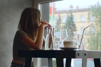 Soft focus portrait of pretty young girl behind the table with cold cocktail and wine glass. (Image